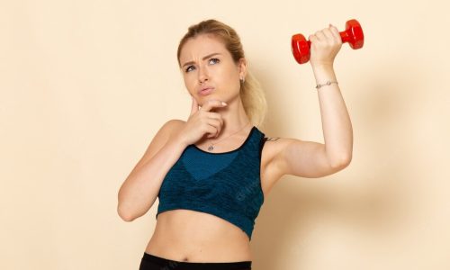 mulher-jovem-de-frente-para-o-esporte-segurando-halteres-vermelhos-e-pensando-na-parede-branca-esporte-corpo-saude-beleza-treino_140725-85367